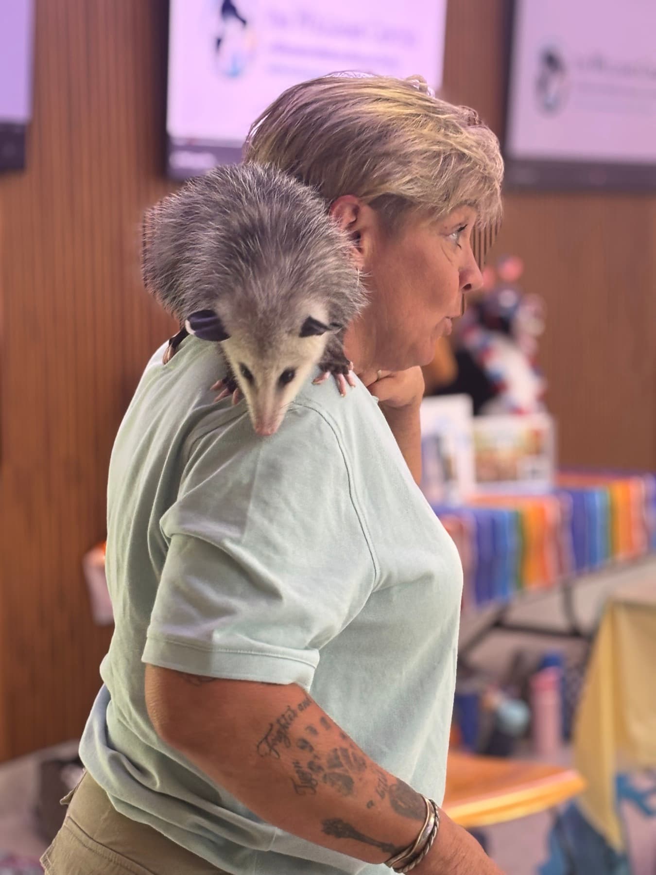 Becky with an opossum resting on her shoulder during a community wildlife presentation